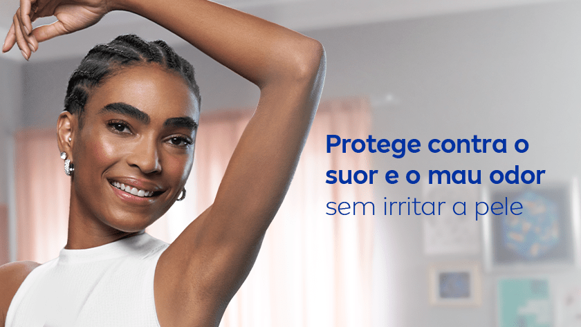 Mulher negra com cabelo trançado e vestido branco mostrando a axila, sorrindo suavemente. Ela está em um ambiente interno iluminado, com cortinas rosadas e quadros desfocados ao fundo. Ao lado, texto azul comunica os benefícios do produto.