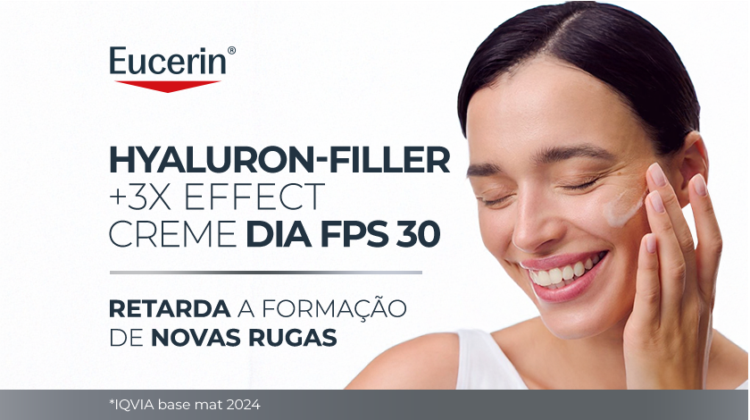 Imagem com fundo branco. Ao lado direito, uma mulher sorri enquanto aplica suavemente o produto no rosto.