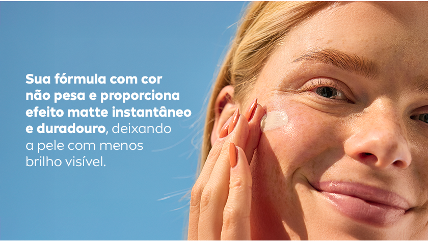 Fundo azul. Ao lado direito, uma mulher sorri, enquanto aplica o protetor solar no rosto.