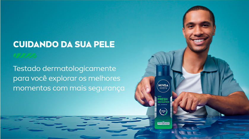 Homem negro sorridente vestindo camiseta verde e camisa azul clara aberta, segurando o desodorante. Texto em branco à esquerda destacando teste dermatológico e segurança para a pele.
