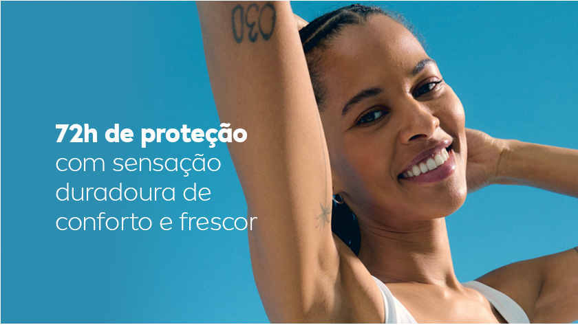 Mulher sorri, enquanto levanta o braço e exibe sua axila. Ela usa uma regata branca e o céu é azul.
