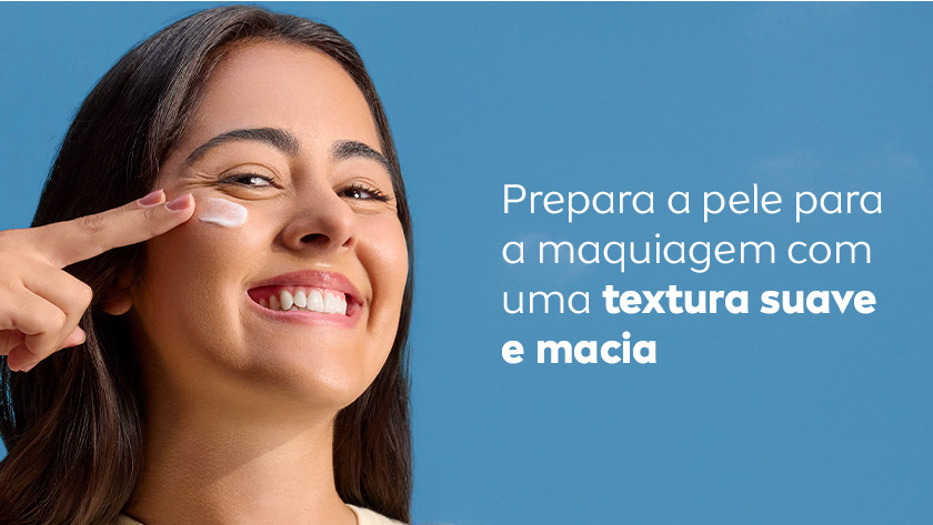 Fundo azul claro. Mulher sorridente aplica creme no rosto com o dedo indicador. À direita, texto branco destaca que o produto prepara a pele para maquiagem com textura suave e macia.