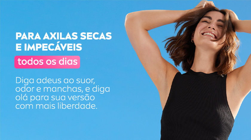 Uma mulher sorri, enquanto levanta os braços e exibe suas axilas. Ela usa uma regata preta, e o fundo é um céu azul.