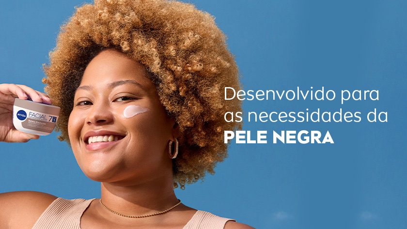 Fundo azul claro. Mulher segura o pote NIVEA Facial 7 em 1 com rótulo bronze e sorri. Creme está aplicado em sua bochecha. À direita, texto destaca que o produto é desenvolvido para as necessidades da pele negra.