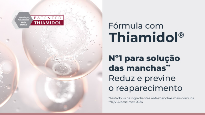 Banner publicitário com fundo claro, mostrando esferas translúcidas em tons de rosa e branco, com textura interna que lembra moléculas ou células, remetendo à ideia de ciência e eficácia. À esquerda, um selo hexagonal cinza e vermelho destaca a patente do ingrediente ativo Thiamidol.