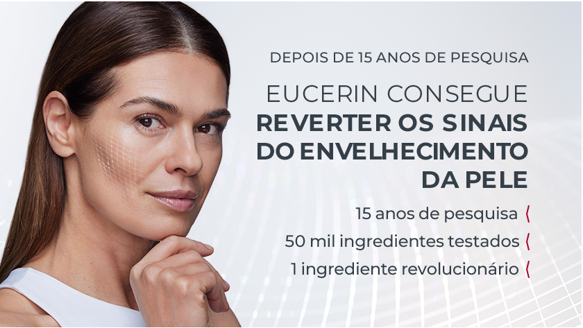Fundo neutro, ao lado esquerdo, uma mulher coloca a mão no queixo e olha para frente.