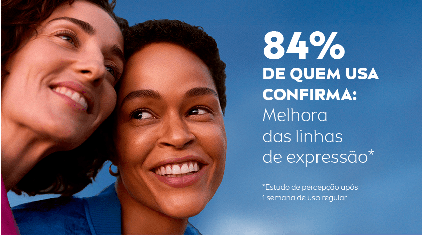 Duas mulheres sorrindo lado a lado, o fundo é um céu azul.