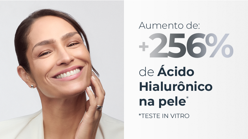 Imagem com fundo branco. Ao lado esquerdo, uma mulher sorri com a mão no rosto.