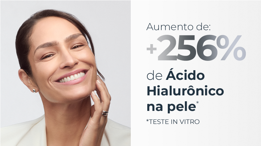 Imagem com fundo branco. Ao lado esquerdo, uma mulher sorri com a mão no rosto.