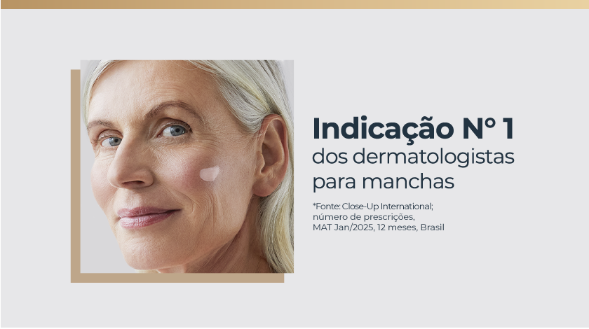 Mulher de pele clara e cabelos grisalhos presos, olhando para a frente, com um pouco de creme aplicado na bochecha.