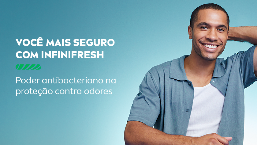 Segurança com Infinifresh Poder antibacteriano e proteção prolongada Homem negro sorridente vestindo camiseta cinza clara, com fundo azul claro. Texto à esquerda destacando a segurança do INFINIFRESH na proteção contra odores.