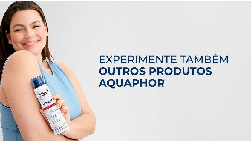 Imagem com fundo neutro. Ao lado direito, uma mulher sorri enquanto segura o Spray Aquaphor.