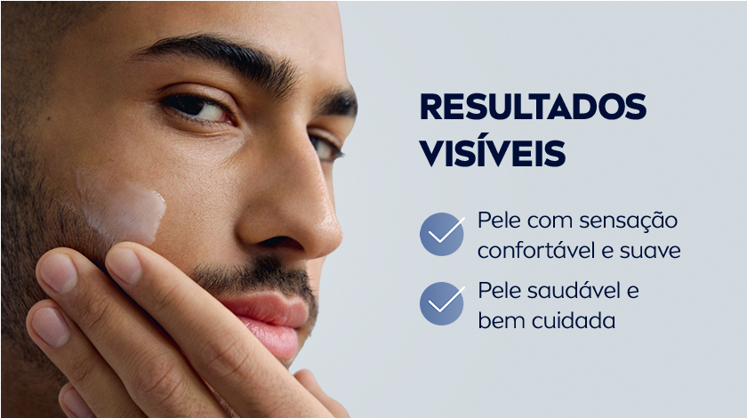 Homem passando creme de barbear no rosto. O fundo é cinza claro.