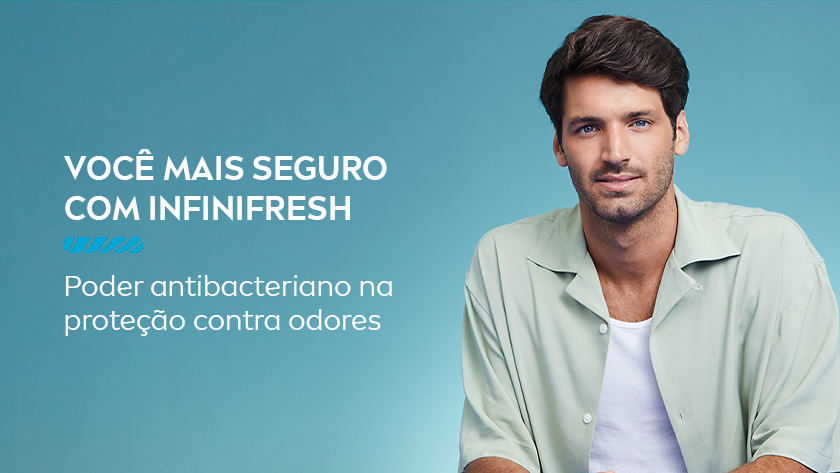 Você mais seguro com infinifresh Poder antibacteriano na proteção contra odores. Um homem com roupas neutras olha para frente, enquanto sorri suavemente. O fundo é azul claro.