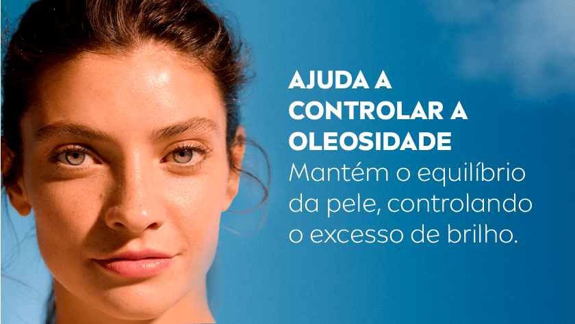 Uma mulher sorri suavemente olhando para frente. O fundo é um céu azul.