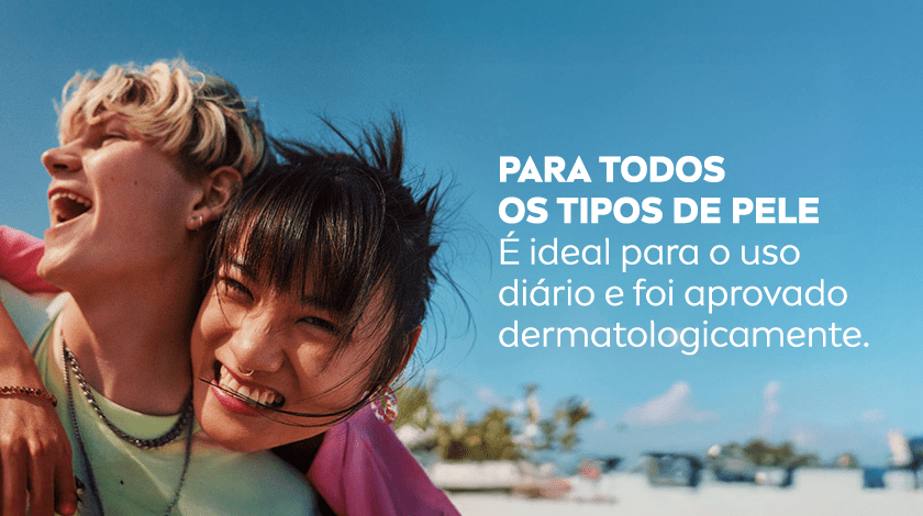 Fundo azul com céu e vegetação tropical ao fundo. No centro, duas pessoas sorrindo e se abraçando, com aparência alegre e natural.