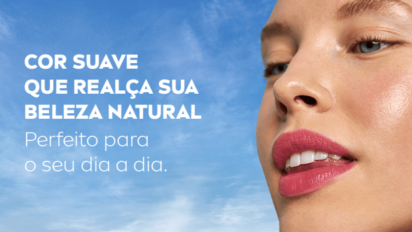 Mulher com expressão confiante e sorriso no canto dos lábios, olhando para o lado, fundo de céu azul.