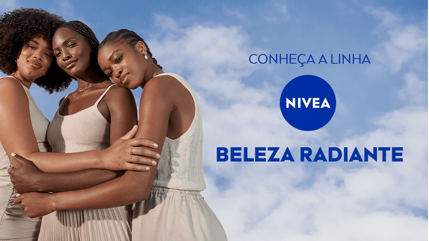 Três mulheres negras com diferentes tons de pele e cabelos naturais abraçadas, sorrindo suavemente, em frente a um céu azul com nuvens.