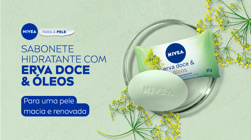 Fundo verde claro. À esquerda, aparecem os textos promocionais da NIVEA em azul escuro e branco. À direita, estão os produtos em destaque: uma embalagem de sabonete com detalhes em verde, acompanhada de uma unidade do sabonete em barra esverdeado com a marca “NIVEA” gravada no centro. Flores de erva-doce decoram a cena, o produto está dentro de um pequeno prato redondo de vidro.