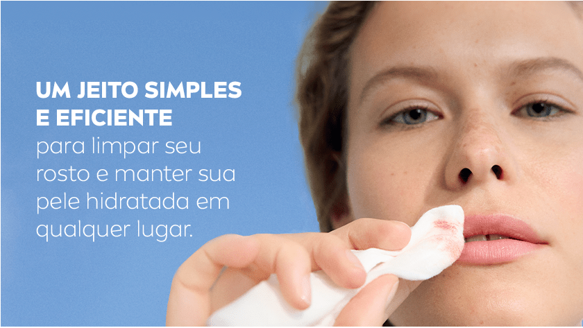 Mulher segura o lenço, enquanto passa nos lábios removendo a maquiagem. O fundo é um céu azul.