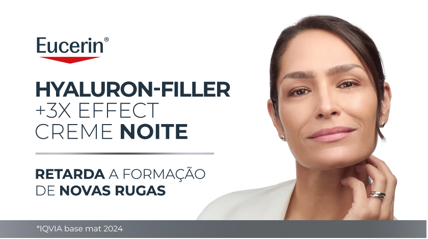 Imagem com fundo branco. Ao lado direito, uma mulher sorri enquanto aplica suavemente o produto no rosto.