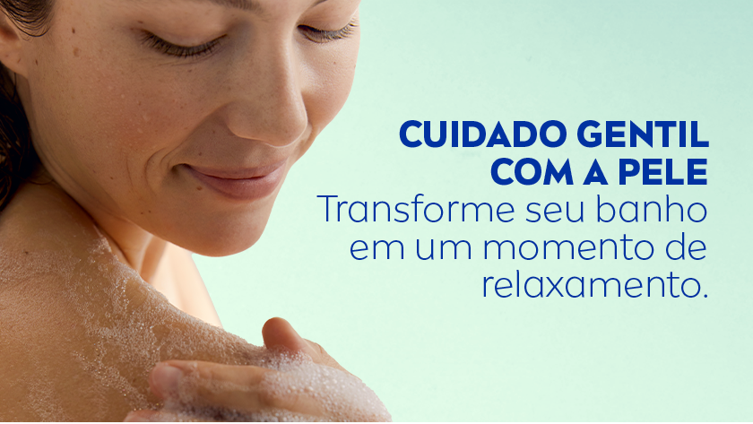 Mulher de pele clara e cabelos castanhos escuros molhados aparece sorrindo suavemente enquanto ensaboa o ombro com espuma. O fundo é verde claro. À direita, há o texto da NIVEA em azul escuro.