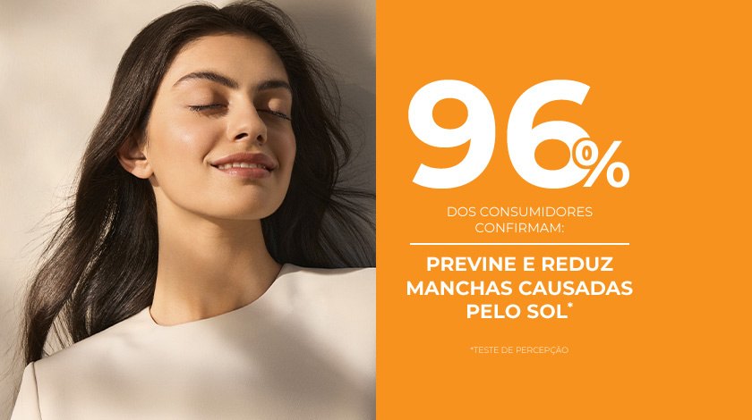 Uma mulher de pele saudável e radiante sorri ao lado de um fundo laranja.