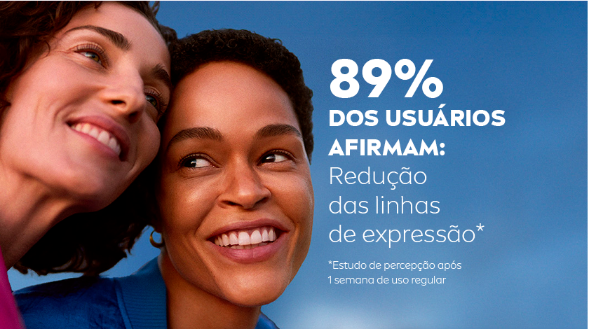 Duas mulheres sorrindo lado a lado, o fundo é um céu azul.