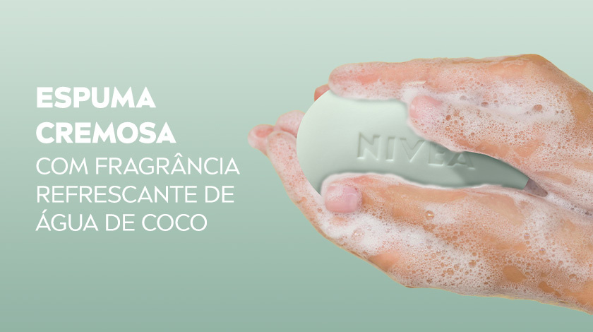 Mão segurando sabonete NIVEA verde-claro ensaboado, produzindo espuma cremosa.
