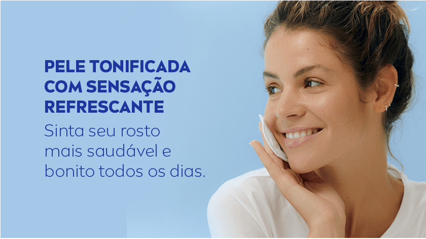 Mulher sorri, enquanto passa um algodão no rosto. O fundo é azul claro.