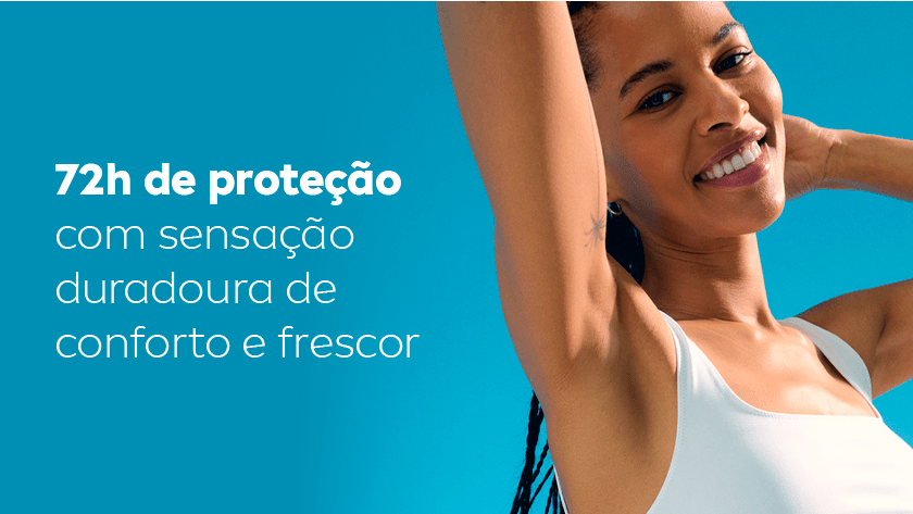 Mulher sorri, enquanto levanta o braço e exibe sua axila. Ela usa uma regata branca e o céu é azul.