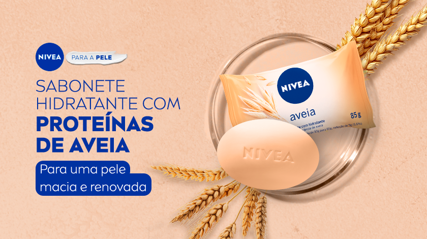 Fundo salmão. À esquerda, aparecem os textos promocionais da NIVEA em azul escuro e branco. À direita, estão os produtos em destaque: uma embalagem de sabonete com detalhes alaranjados, acompanhada de uma unidade do sabonete em barra de cor salmão com a marca “NIVEA” gravada no centro. Galinhos de aveias decoram a cena, o produto está dentro de um pequeno prato redondo de vidro.