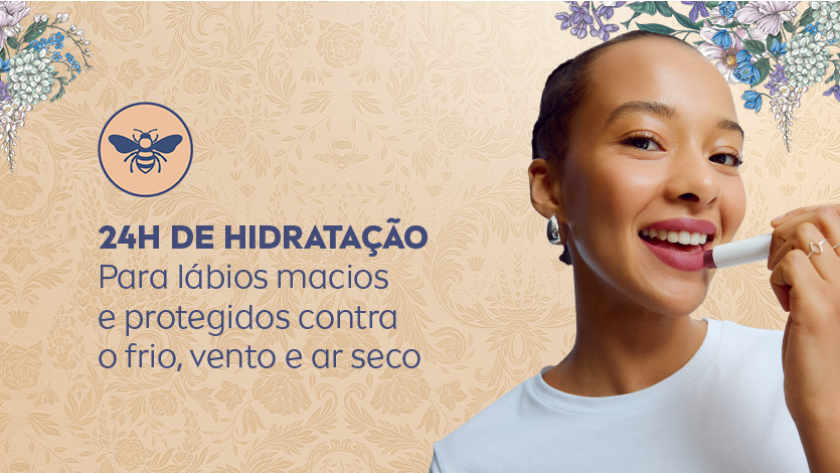 Mulher sorridente aplicando hidratante labial. O fundo é claro, com iluminação suave e elementos florais sutis em tons pastel, criando uma atmosfera delicada e acolhedora.