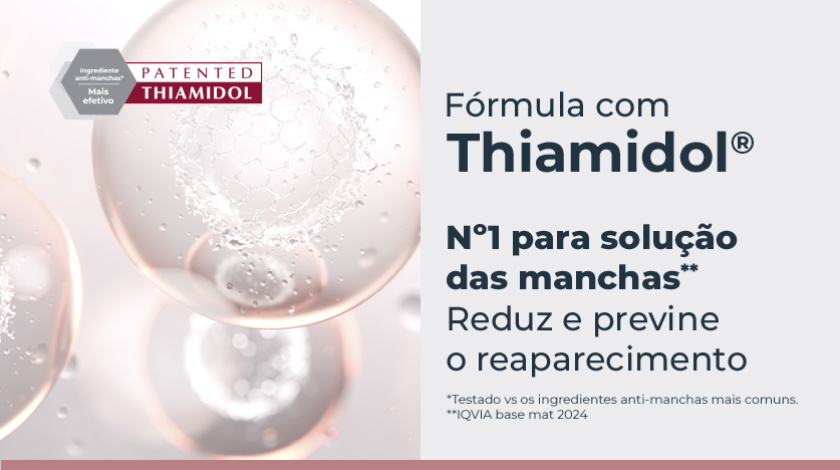 Banner publicitário com fundo claro, mostrando esferas translúcidas em tons de rosa e branco, com textura interna que lembra moléculas ou células, remetendo à ideia de ciência e eficácia. À esquerda, um selo hexagonal cinza e vermelho destaca a patente do ingrediente ativo Thiamidol.