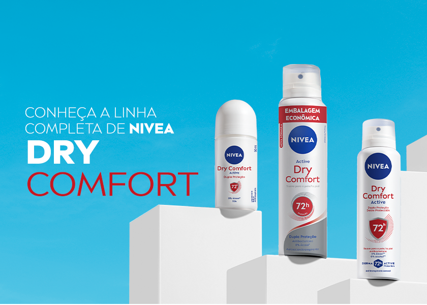 Fundo azul vibrante e blocos brancos em diferentes alturas no canto inferior. Sobre os blocos, estão três produtos da linha NIVEA Dry Comfort: um desodorante roll-on, um Dry Comfort embalagem econômica de 200ml e um de 150ml. Todos têm embalagem branca com tampa branca e detalhes em vermelho.